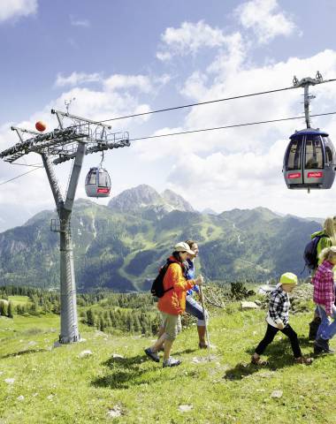 Familie beim Wandern neben Seilbahn in Österreich